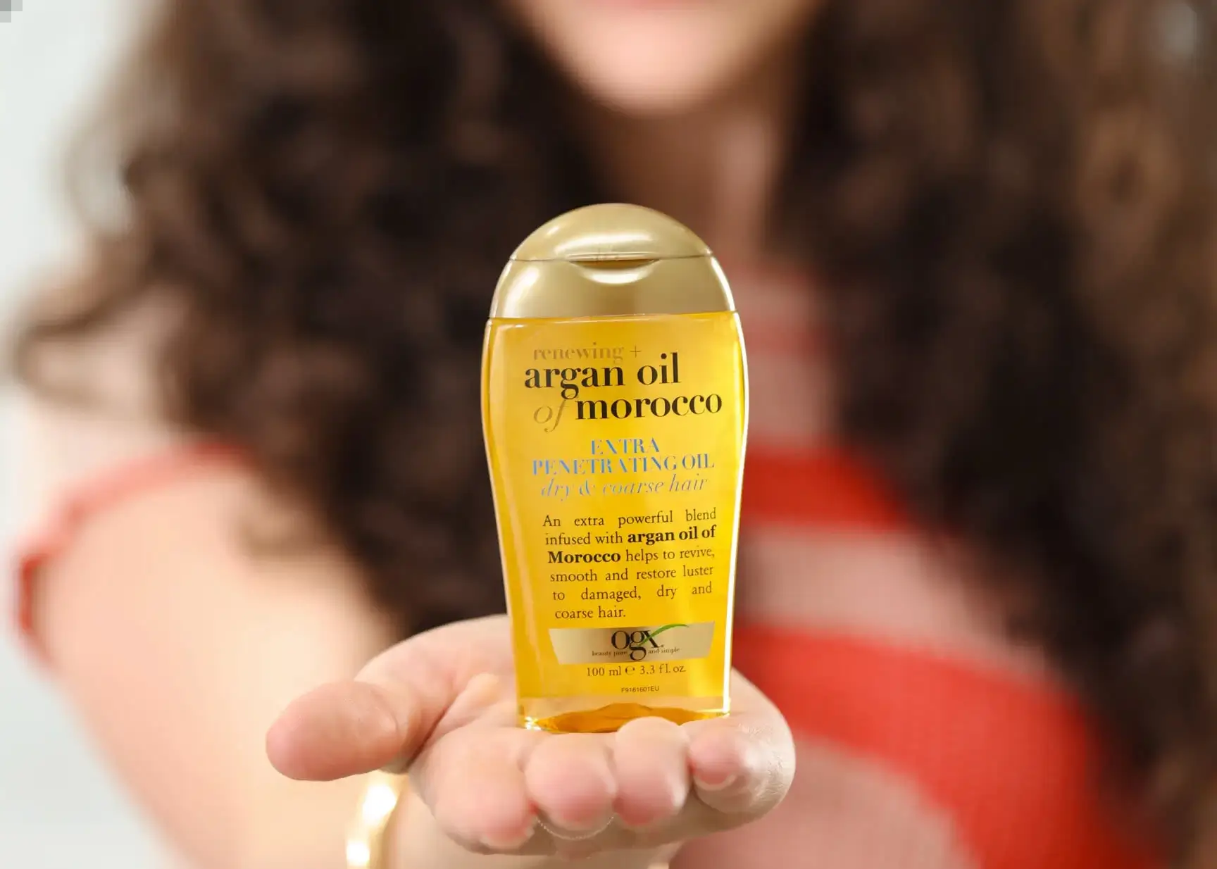 Imagine displaying woman with healthy hair holding OGX Argan Oil of Morrocco Extra Penetrating Oil
